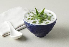 es cendol ou dawet é sobremesa gelada tradicional da indonésia feita de farinha de arroz, açúcar de palma, leite de coco e folha de panda servida em vidro na mesa de bambu. popular durante o jejum no ramadã. foto