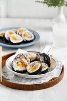 bap de arroz branco cozido no vapor e vários outros ingredientes, como kyuri, cenoura, salsicha, vara de caranguejo ou kimchi e envolto com pia de algas marinhas. foto