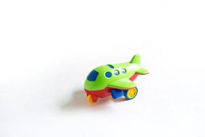 avião de plástico verde de brinquedo com detalhes coloridos de vermelho, azul e amarelo em um fundo branco. brinquedo para uma criança, o conceito de turismo e viagens, viagens aéreas. espaço para texto foto