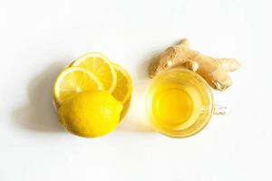 chá medicinal em uma xícara, gengibre, limão-fortalecer o sistema imunológico na estação fria. bebida vitamínica para saúde e ingredientes em um fundo branco. foto