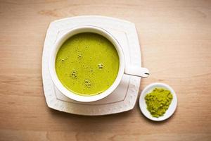 chá verde matcha japonês é derramado em uma caneca branca e em um pires branco em pó. conjunto de chá em um guardanapo texturizado. bebida revigorante em um café, culinária, alegria, antioxidante. espaço para texto foto