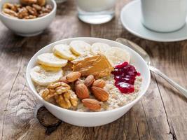 um farto e saudável café da manhã de aveia com nozes, amêndoas e manteiga de amendoim. comida deliciosa, uma fonte de carboidratos lentos. foto