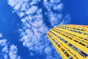 o prédio amarelo e céu azul, nuvens brancas foto