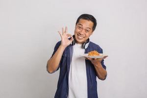 homem asiático comendo macarrão instantâneo e se surpreenda com o quão delicioso é foto