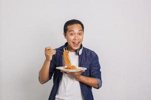 homem asiático comendo macarrão instantâneo e se surpreenda com o quão delicioso é foto