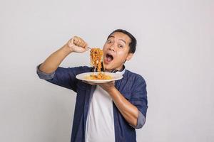 homem asiático comendo macarrão instantâneo e se surpreenda com o quão delicioso é foto