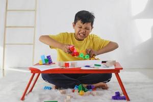 birra emocional e menino com raiva enquanto jogava brinquedos em casa. experiência traumática na infância, psicologia, psicológica, síndrome de asperger, transtorno de asperger, autista, autismo. foto