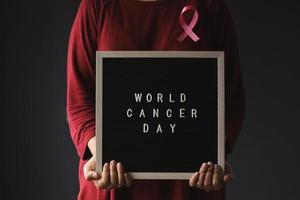 mulher usando fita rosa e quadro de mensagens para o dia mundial do câncer e conscientização do câncer de mama foto