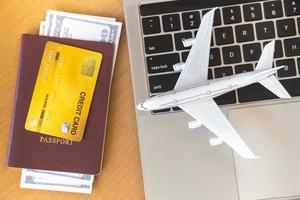 passagens aéreas, passaportes e cartão de crédito perto de computador portátil e avião na mesa. conceito de reserva de bilhetes online foto