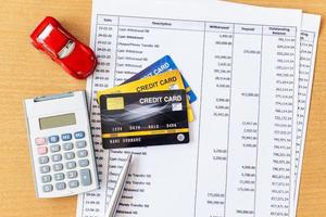 modelo de carro e calculadora no extrato bancário e cartão de crédito em uma mesa de madeira. foto