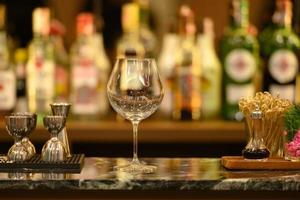 vidro transparente no tampo da mesa de mármore preto e belas prateleiras bokeh com garrafas de álcool
