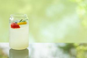 delicioso refrigerante de limão fresco suculento na mesa de vidro fundo de reflexão de folha turva foto