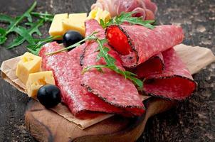 sanduíche com salsicha, azeitona, tomate e rúcula no antigo fundo de madeira foto