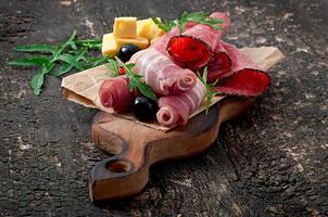 sanduíche com salsicha, azeitona, tomate e rúcula no antigo fundo de madeira foto