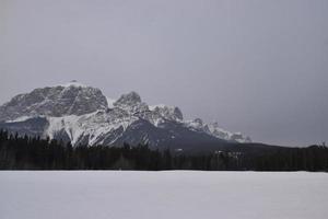 montanhas rochosas cobertas de neve com lago congelado em primeiro plano foto