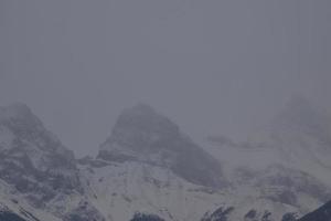 montanhas rochosas cobertas de neve com céu cinza nebuloso foto