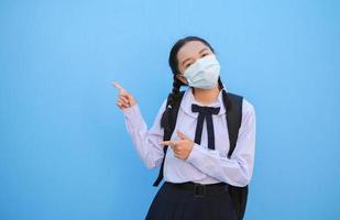 menina da escola usa máscara em fundo azul, de volta à escola. foto