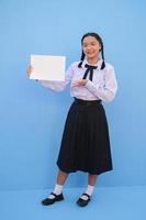 menina da escola segurando outdoor sobre fundo azul. foto