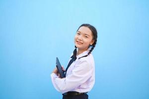 menina da escola segurando o tablet sobre fundo azul. foto