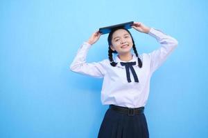 menina da escola segurando o tablet sobre fundo azul. foto