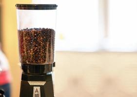 grãos de café na máquina de recipiente de mistura na cafeteria foto