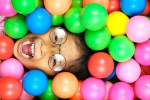 retrato de uma menina sorrindo amplamente com bolas de plástico coloridas ao seu redor foto