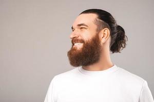 retrato de vista lateral de homem alegre hipster barbudo sorrindo sobre fundo cinza