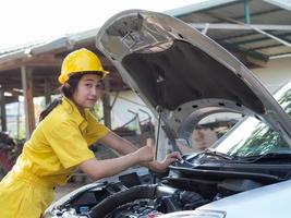 mulheres em uniformes de trabalho estão medindo os níveis de óleo do motor do carro