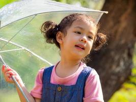uma garotinha estava feliz em um guarda-chuva contra a chuva foto