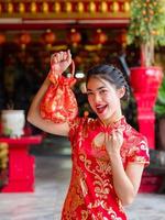 mulheres asiáticas em trajes nacionais chineses seguram saco de saudação para o evento do ano novo chinês foto