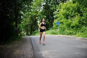 garota esportiva no sportswear correndo em um parque verde e treinando na natureza. um estilo de vida saudável. foto