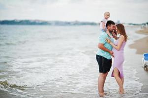 férias de verão. pais e pessoas atividade ao ar livre com crianças. boas férias em família. pai, mãe grávida, filha bebê na praia de areia do mar. foto