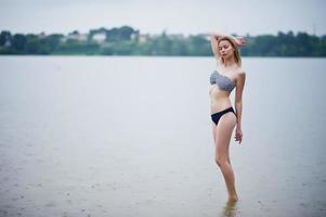 retrato de uma bela modelo de biquíni em pé e posando na água. foto