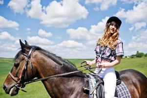 menina bonita andando a cavalo em um campo em dia ensolarado. foto