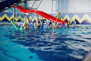 grupo de fitness de meninas fazendo exercícios aeróbicos na piscina do parque aquático. atividades esportivas e de lazer. foto