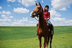 menina bonita andando a cavalo em um campo em dia ensolarado. foto