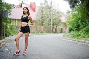 garota esportiva no sportswear exercitando em um parque verde e treinando na natureza. um estilo de vida saudável. foto