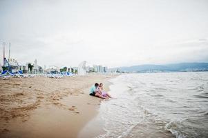 férias de verão. pais e pessoas atividade ao ar livre com crianças. boas férias em família. pai, mãe grávida, filha bebê na praia de areia do mar. foto