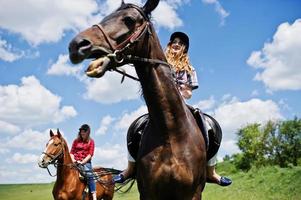 rebocar meninas bonitas montando um cavalo em um campo em dia ensolarado foto