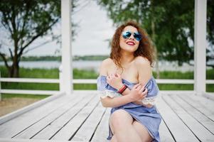 retrato de uma jovem fabulosa vestindo roupa chique posando em um terraço de madeira branco. foto