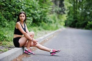 garota esportiva no sportswear descansando em um parque verde após o treino na natureza. um estilo de vida saudável. foto