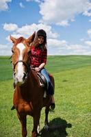 menina bonita andando a cavalo em um campo em dia ensolarado. foto