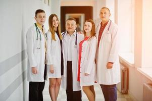 grupo de jovens médicos em jalecos brancos posando no hospital. foto