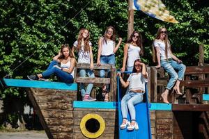 seis garota fabulosa se divertindo posando em um navio de madeira infantil no parque. foto