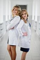 duas belas médicas ou trabalhadores médicos em jalecos brancos posando no hospital. foto
