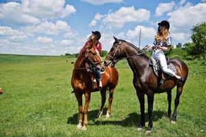 rebocar meninas bonitas montando um cavalo em um campo em dia ensolarado foto