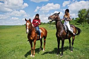 rebocar meninas bonitas montando um cavalo em um campo em dia ensolarado foto