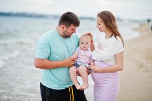 férias de verão. pais e pessoas atividade ao ar livre com crianças. boas férias em família. pai, mãe grávida, filha bebê na praia de areia do mar. foto