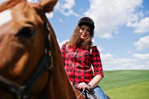 menina bonita andando a cavalo em um campo em dia ensolarado. foto