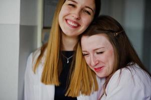 duas belas médicas ou trabalhadores médicos em jalecos brancos posando no hospital. foto